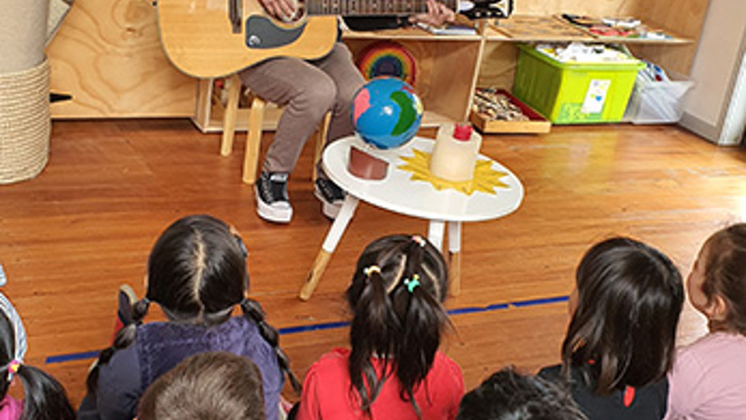 Teacher and children singing peace at Little Earth Montessori Remuera childcare